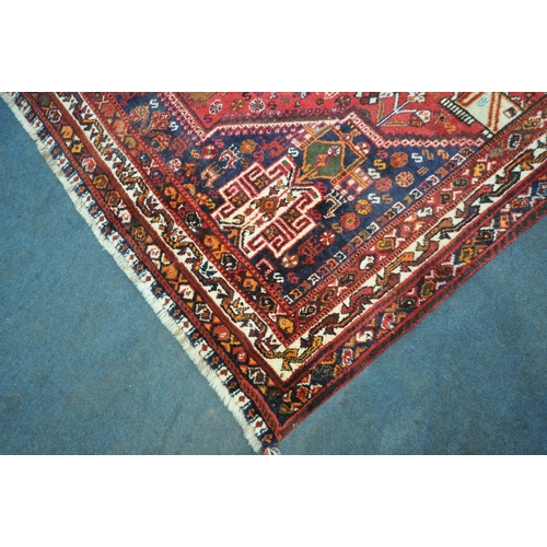 221 - A HAND WOVEN RED GROUND IRANIAN KASHGAI RECTANGULAR RUG, with repeating geometric patterns, surround... 