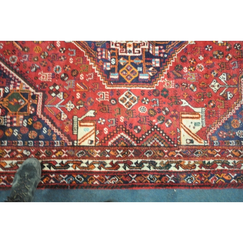 221 - A HAND WOVEN RED GROUND IRANIAN KASHGAI RECTANGULAR RUG, with repeating geometric patterns, surround... 