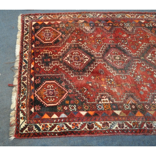 222 - A RED GROUND SHIRAZ RUG, with repeating geometric patterns, united by a multi-strap border, 173cm x ... 