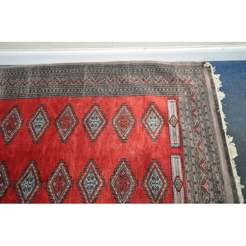 279 - A LARGE RED GROUND RECTANGULAR RUG, with forty-four central medallions, surrounded by a multi-strap ... 