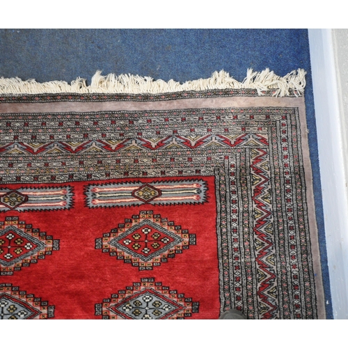 279 - A LARGE RED GROUND RECTANGULAR RUG, with forty-four central medallions, surrounded by a multi-strap ... 