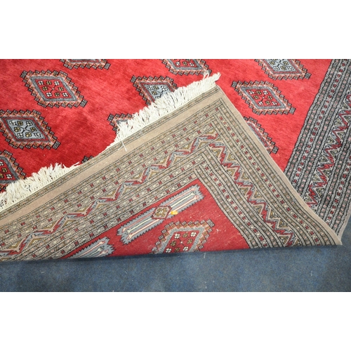 279 - A LARGE RED GROUND RECTANGULAR RUG, with forty-four central medallions, surrounded by a multi-strap ... 