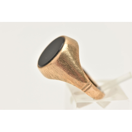 438 - A GENTS 9CT GOLD ONYX SIGNET RING, set with a polished oval onyx inlay, collet set to a worn texture... 