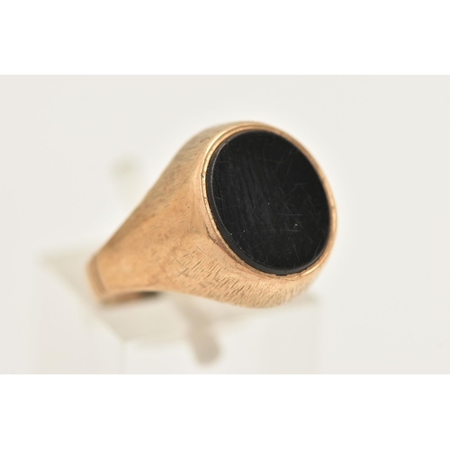 438 - A GENTS 9CT GOLD ONYX SIGNET RING, set with a polished oval onyx inlay, collet set to a worn texture... 