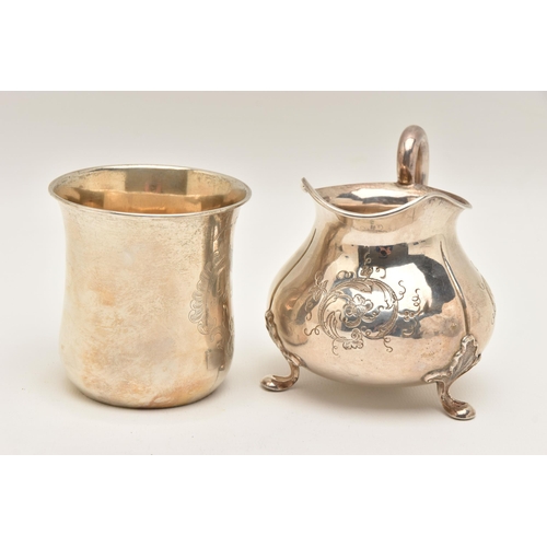 483 - TWO WHITE METAL ITEMS, to include a cream jug with engraved floral pattern, raised on three leaf det... 