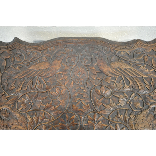 160 - A 20TH CENTURY INDIAN OAK SEWING TABLE, with intricate carved details, the top depicting two birds a... 