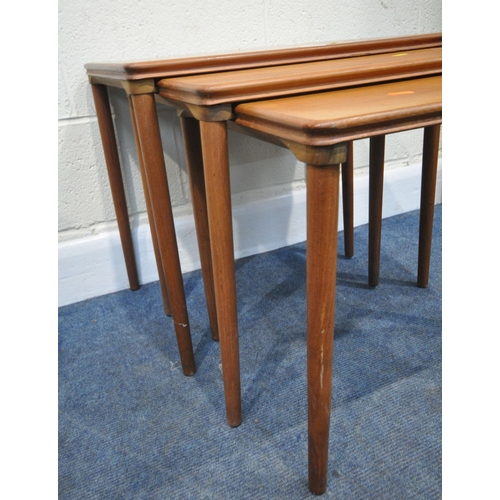 165 - A MID CENTURY TEAK NEST OF THREE TABLES, raised on cylindrical tapered legs, largest table width 56c... 