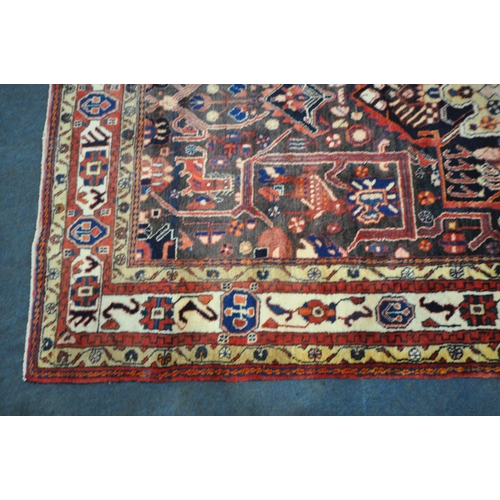 189 - A LARGE RECTANGULAR WOOLEN RUG, with mirrored and repeating geometric patterns, surrounded by a mult... 