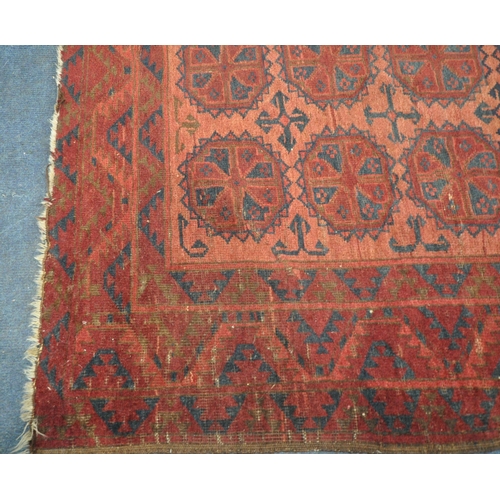 190 - A RED GROUND RECTANGULAR AFGHAN RUG, with twenty-one central medallions, surrounded by a multi-strap... 