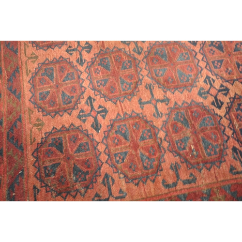 190 - A RED GROUND RECTANGULAR AFGHAN RUG, with twenty-one central medallions, surrounded by a multi-strap... 