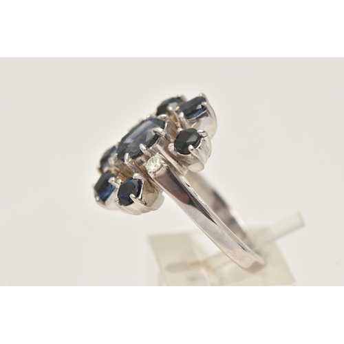 416 - A WHITE METAL SAPPHIRE AND DIAMOND CLUSTER RING, set with a central oval cut sapphire, flanked with ... 