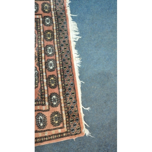 192 - A SALMON PINK GROUND WOOLEN TEKKE RUG, with twenty-eight central medallions, surrounded by a multi-s... 