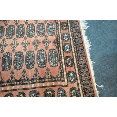 192 - A SALMON PINK GROUND WOOLEN TEKKE RUG, with twenty-eight central medallions, surrounded by a multi-s... 