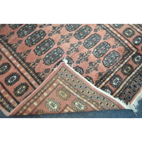 192 - A SALMON PINK GROUND WOOLEN TEKKE RUG, with twenty-eight central medallions, surrounded by a multi-s... 