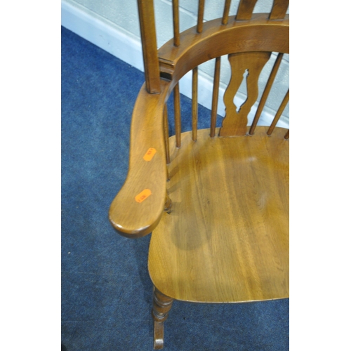 224 - A 20TH CENTURY OAK ROCKING CHAIR, with a central splat, swept armrests, raised on turned supports, w... 