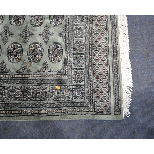 237 - A GREEN GROUND WOOLEN HAND KNOTTED PAKISTANI RUG, with twenty-seven central medallions, surrounded b... 