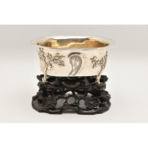 580 - AN EARLY 20TH CENTURY CHINESE SILVER JARDINIERE WITH HARDWOOD BASE, of an oval form, embossed pronus... 