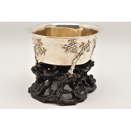 580 - AN EARLY 20TH CENTURY CHINESE SILVER JARDINIERE WITH HARDWOOD BASE, of an oval form, embossed pronus... 