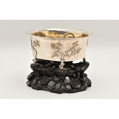 580 - AN EARLY 20TH CENTURY CHINESE SILVER JARDINIERE WITH HARDWOOD BASE, of an oval form, embossed pronus... 