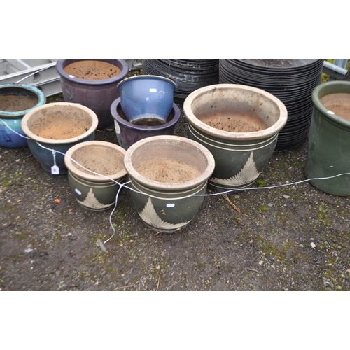 40 - A COLLECTION OF GLAZED PLANT POTS AND PLASTIC POT PLATES including a graduated green set of three (t... 