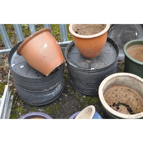 40 - A COLLECTION OF GLAZED PLANT POTS AND PLASTIC POT PLATES including a graduated green set of three (t... 