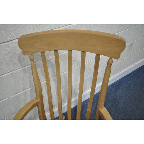 156 - A BEECH FRAMED ROCKING CHAIR, with swept armrests, supported by spindles, raised on turned supports,... 