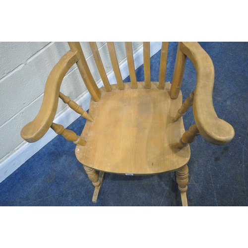 156 - A BEECH FRAMED ROCKING CHAIR, with swept armrests, supported by spindles, raised on turned supports,... 