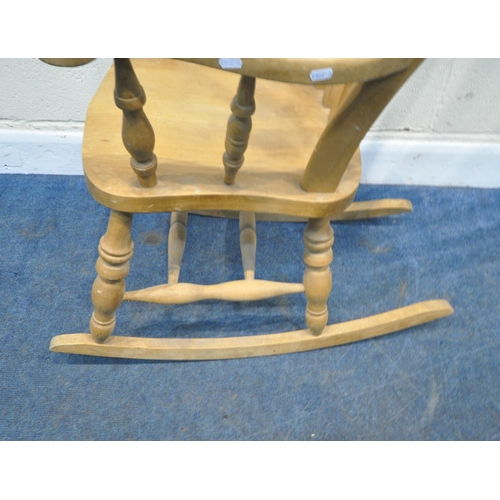 156 - A BEECH FRAMED ROCKING CHAIR, with swept armrests, supported by spindles, raised on turned supports,... 