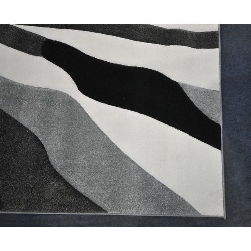 174 - A LARGE RECTANGULAR RUG, with black, white and grey patterns, label to underside reading Canyon 290c... 