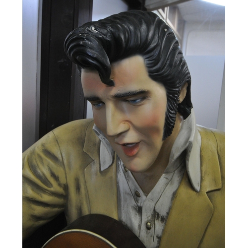 151 - A LIFESIZE FIGURE OF THE WORLD FAMOUS ROCK AND ROLL STAR ELVIS PRESLEY, seated on a stool, playing a... 