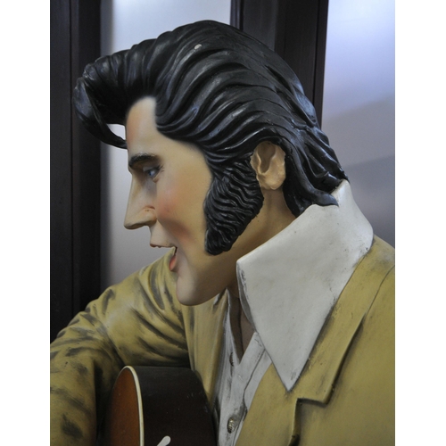 151 - A LIFESIZE FIGURE OF THE WORLD FAMOUS ROCK AND ROLL STAR ELVIS PRESLEY, seated on a stool, playing a... 