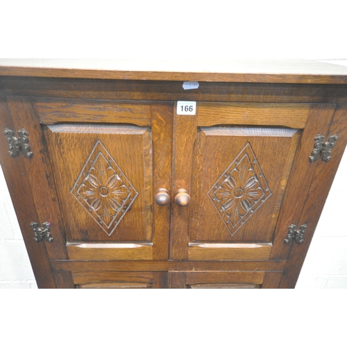 166 - A 20TH CENTURY OAK CABINET, with two pairs of double doors, the smaller pair with geometric patterns... 