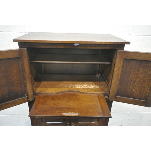 166 - A 20TH CENTURY OAK CABINET, with two pairs of double doors, the smaller pair with geometric patterns... 