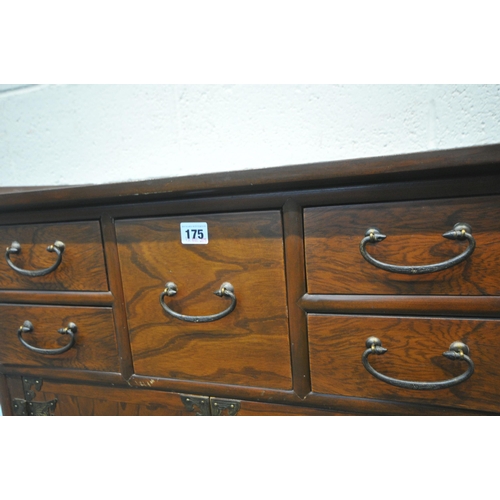 175 - A REPRODUCTION KOREAN ELM LOW CABINET, with a shaped top, brass mounts, six assorted drawers, over d... 