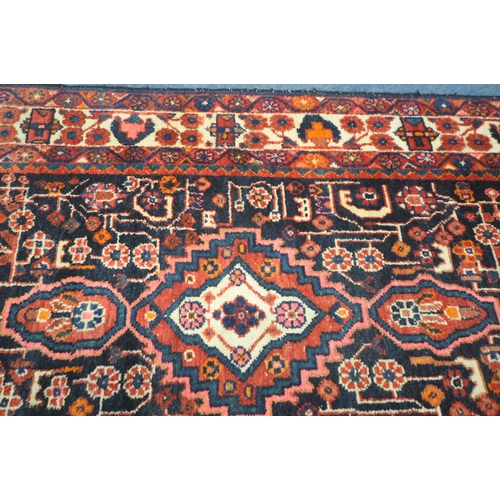 181 - AN IRANIAN WOOLEN RUG, with repeating geometric patterns, surrounded by a multi-strap border, 260cm ... 