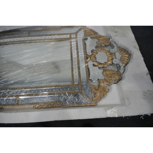 231 - A NEW IN BOX VENETIAN WALL MIRROR, with a foliate gilt frame, 65cm x 140cm, condition report: new in... 