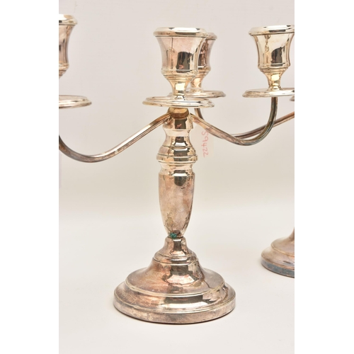 528 - A PAIR OF ELIZABETH II SILVER THREE BRANCH CANDLESTICKS, tapered stems on round weighted bases, hall... 