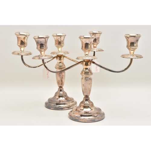 528 - A PAIR OF ELIZABETH II SILVER THREE BRANCH CANDLESTICKS, tapered stems on round weighted bases, hall... 