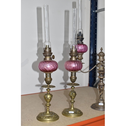 787 - FOUR BRASS AND CRANBERRY GLASS OIL LAMPS all with cranberry glass reservoirs, all have wick raiser k... 