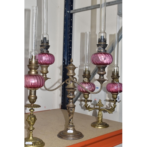 787 - FOUR BRASS AND CRANBERRY GLASS OIL LAMPS all with cranberry glass reservoirs, all have wick raiser k... 