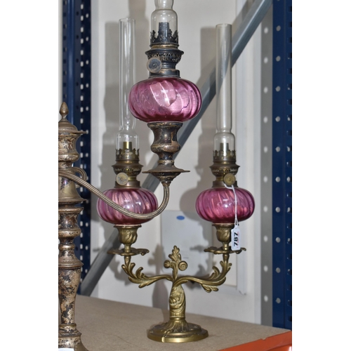 787 - FOUR BRASS AND CRANBERRY GLASS OIL LAMPS all with cranberry glass reservoirs, all have wick raiser k... 