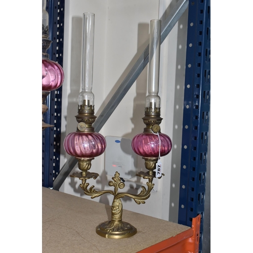 787 - FOUR BRASS AND CRANBERRY GLASS OIL LAMPS all with cranberry glass reservoirs, all have wick raiser k... 