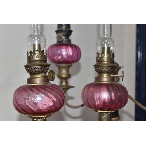 787 - FOUR BRASS AND CRANBERRY GLASS OIL LAMPS all with cranberry glass reservoirs, all have wick raiser k... 