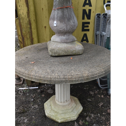 A WEATHERED COMPOSITE CIRCULAR GARDEN TABLE, on a reeded column and ...