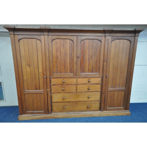 151 - A 19TH CENTURY PITCH PINE WARDROBE, fitted with two large doors, flanking smaller double doors over ... 