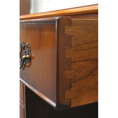 211 - A REPRODUCTION YEW WOOD TWIN PEDESTAL DESK, with a green leather writing surface, fitted with an arr... 