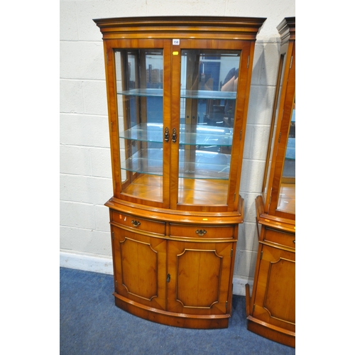 158 - A PAIR OF REPRODUCTION BOW FRONT YEW WOOD DISPLAY CABINETS, the double glazed doors enclosing a mirr... 