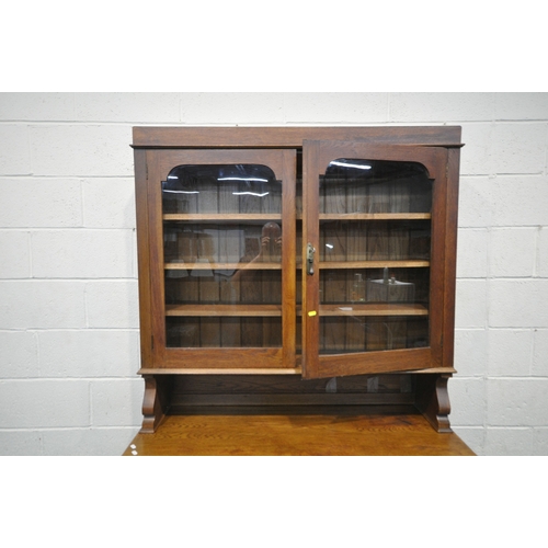 167 - AN ARTS AND CRAFTS OAK DRESSER, the double glass door enclosing three shelves, atop a base with two ... 