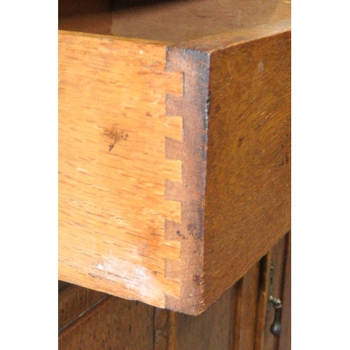 167 - AN ARTS AND CRAFTS OAK DRESSER, the double glass door enclosing three shelves, atop a base with two ... 