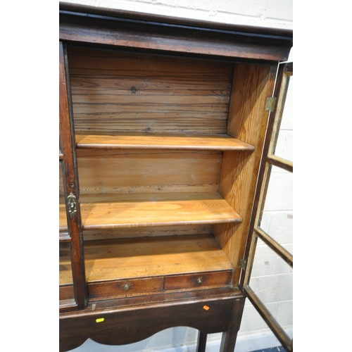 218 - AN OAK CABINET ON STAND, the double glass doors enclosing two shelves and four drawers, width 125cm ... 